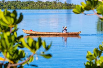 Auki, Solomon Islands - March 20, 2014: Senior woman paddles in a traditional wooden canoe at the Langa Langa Lagoon, on the West coast of Malaita Island, near Auki.