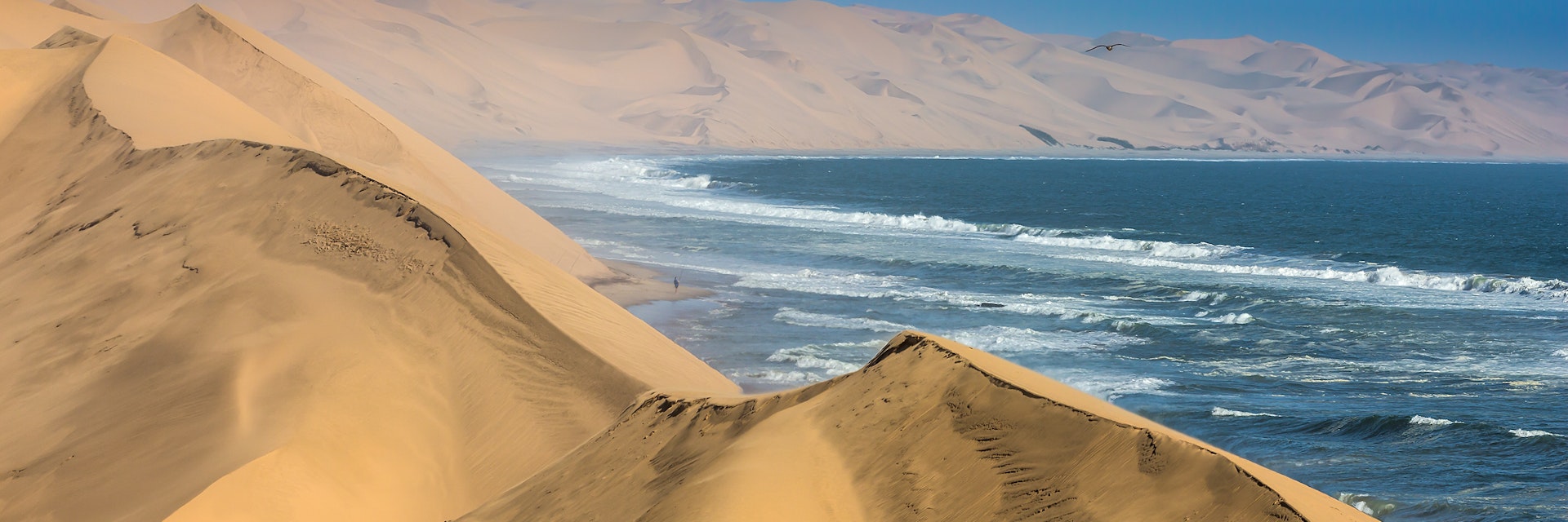 The concept of extreme and exotic tourism. Ocean surf with foamy waves. Gorgeous jeep - safari through the huge sand dunes. Atlantic coast of Walvis Bay, Namibia, south of Africa