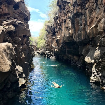 People swimming in the turquoise waters of a pool between tall rock cliffs (Las Grietas), Puerto Ayora, Santa Cruz Island, Ecuador