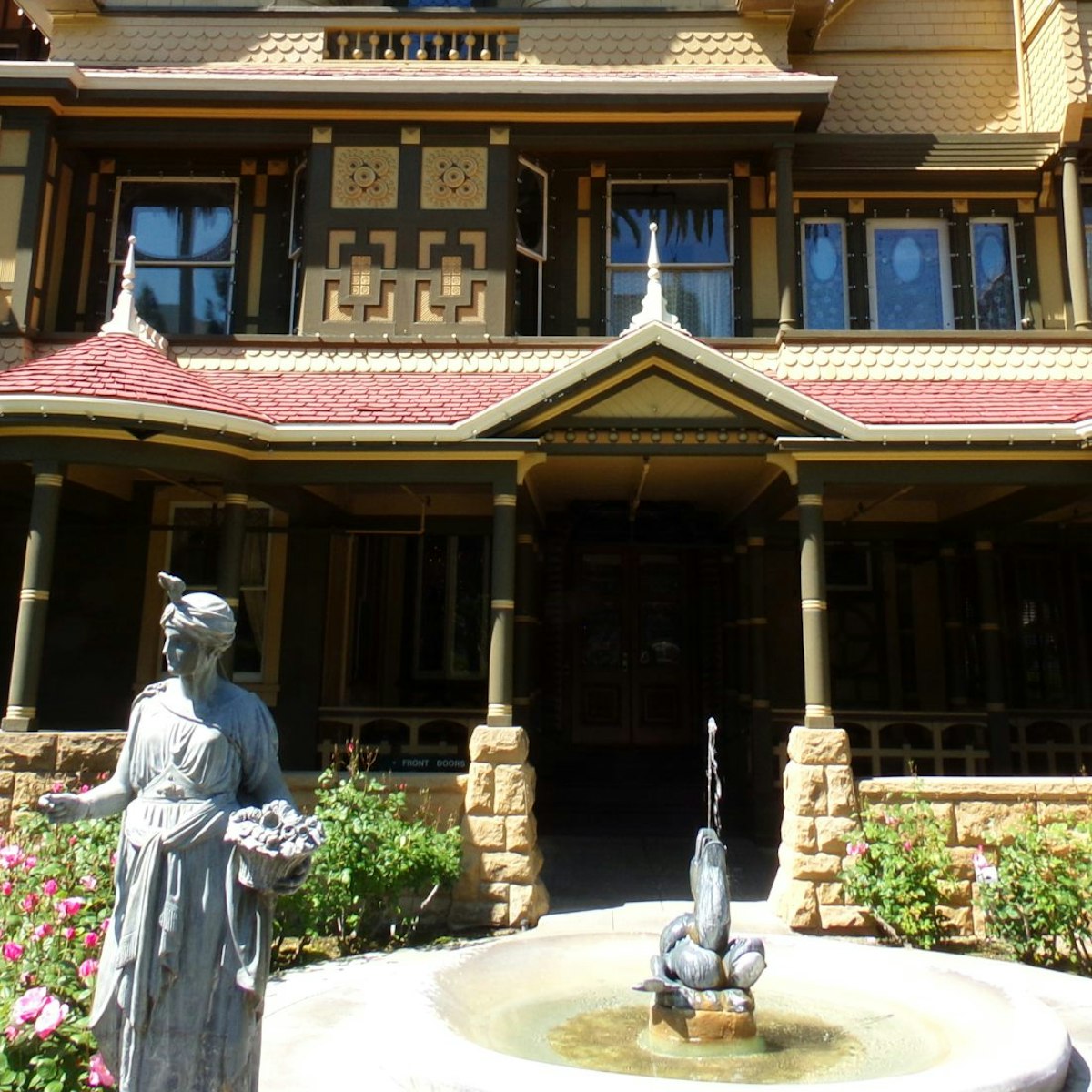 April 2, 2016: Exterior of the Winchester Mystery House with statues and a fountain.