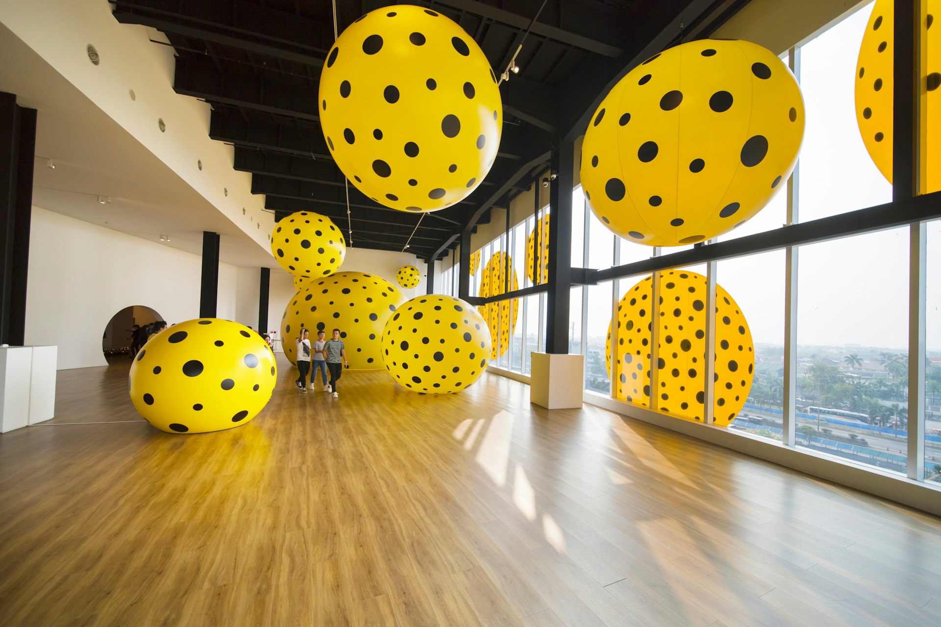 Visitors walking past Kusama's yellow and black-polka-dotted pieces in the Museum Macan.