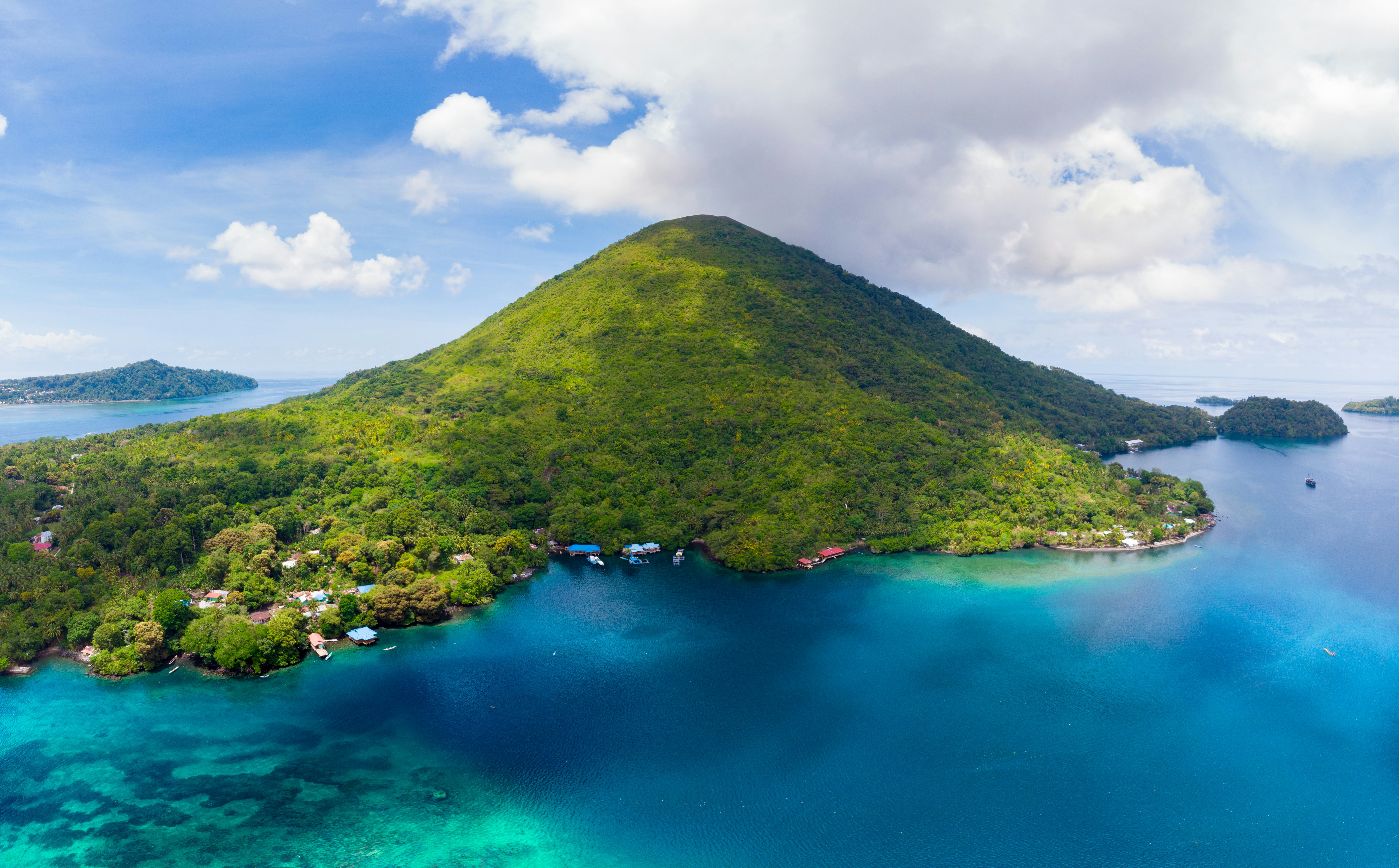 Aerial of Pulau Gunung Api with small buildings dotting the outskirts of the island