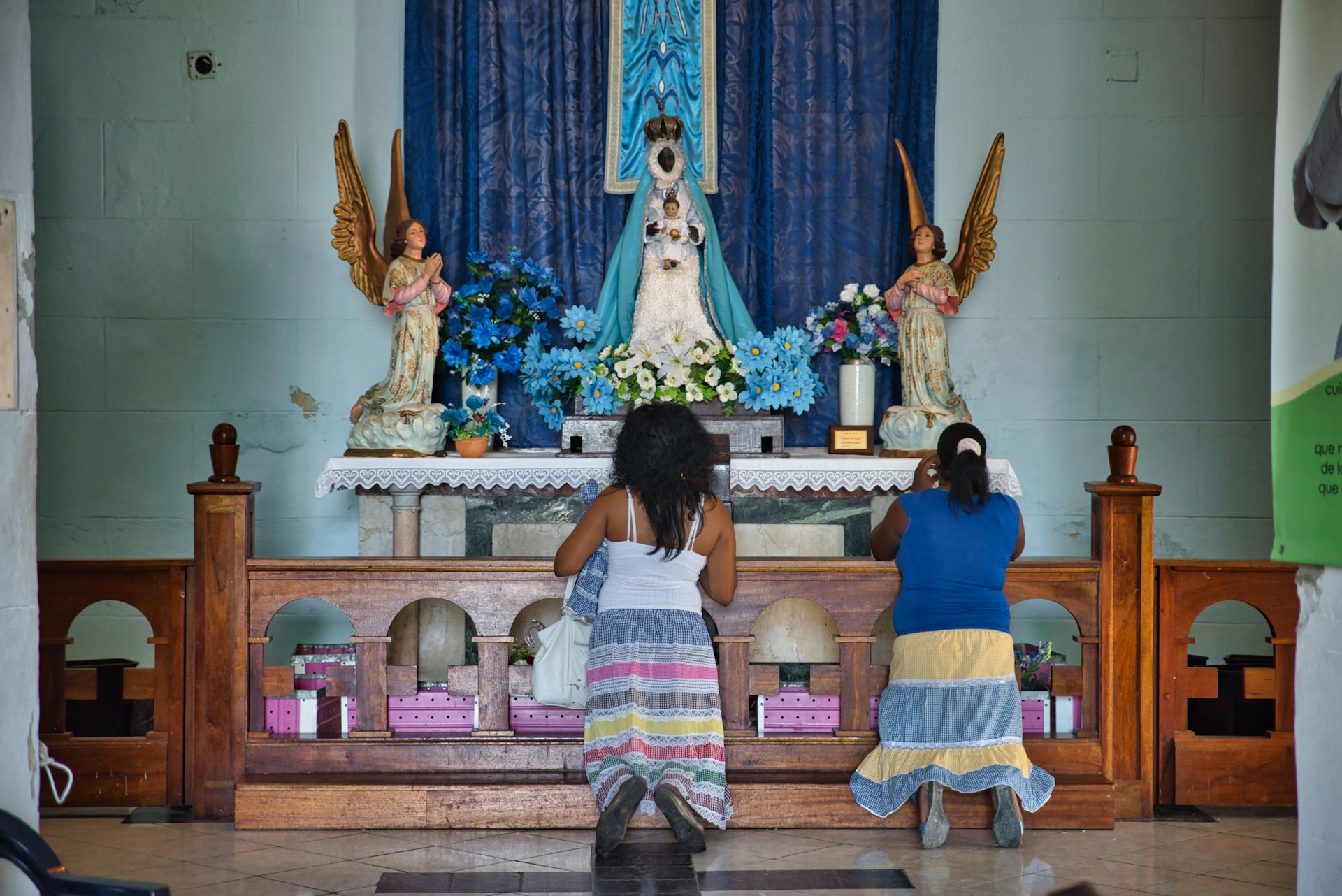 Women praying in front of the altar to Black Madonna at Our Lady of the Regla churc