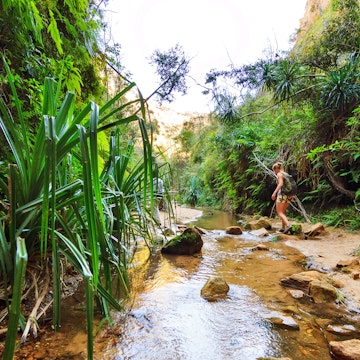 Woman hiking across a small stream in Isalo National Park. 