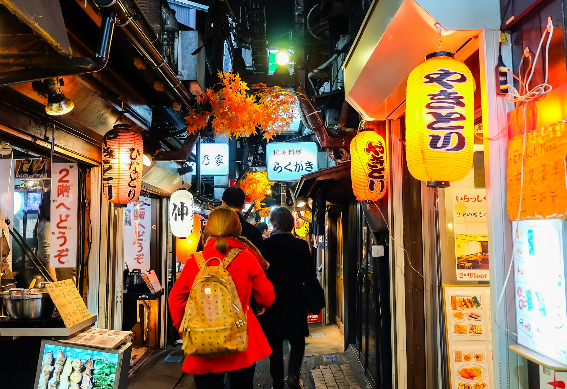 Visitors walking past Japanese style BBQ restaurants at Omoide Yokocho alley at night