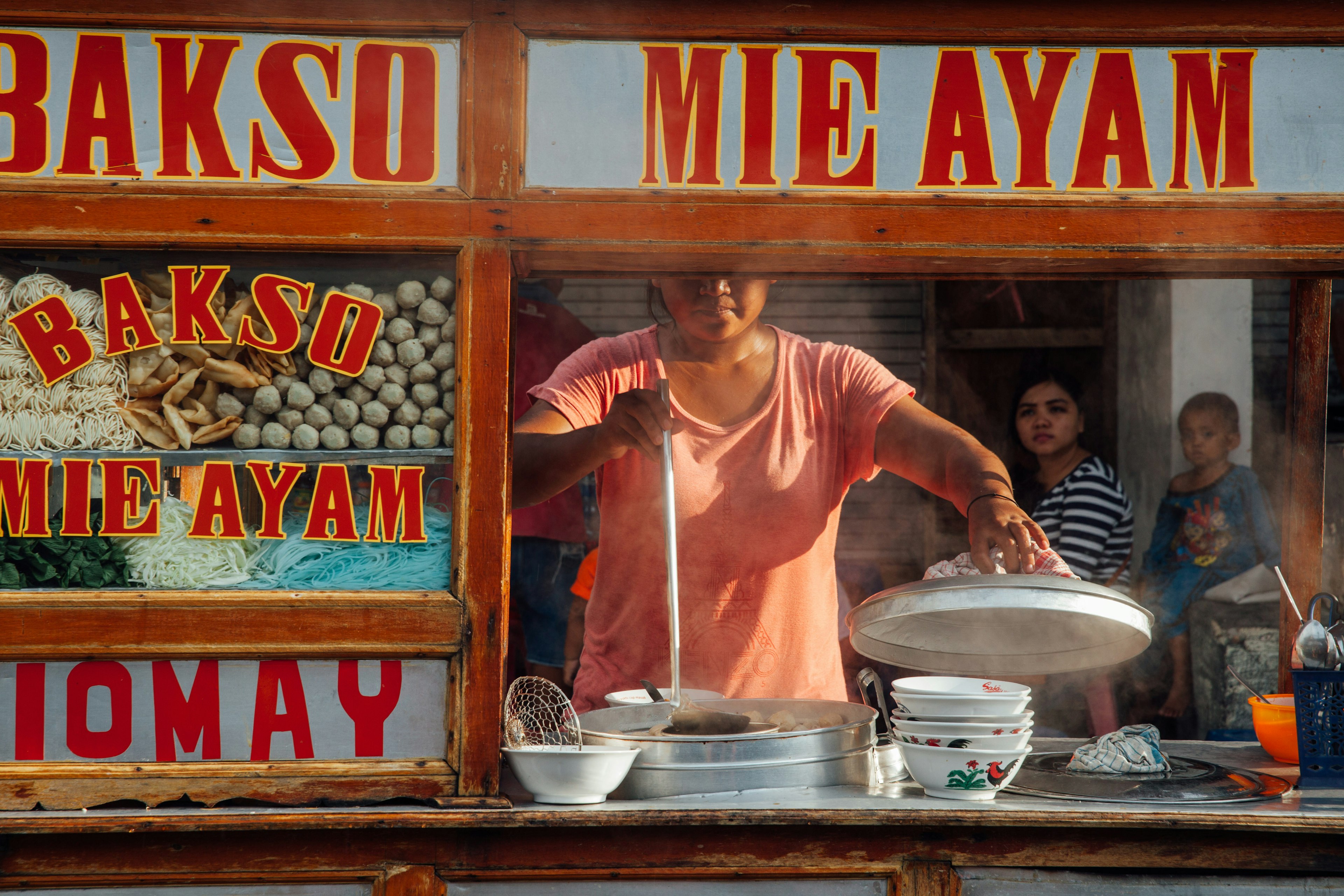 A woman cooking meatball soup at a street stall in Ubud