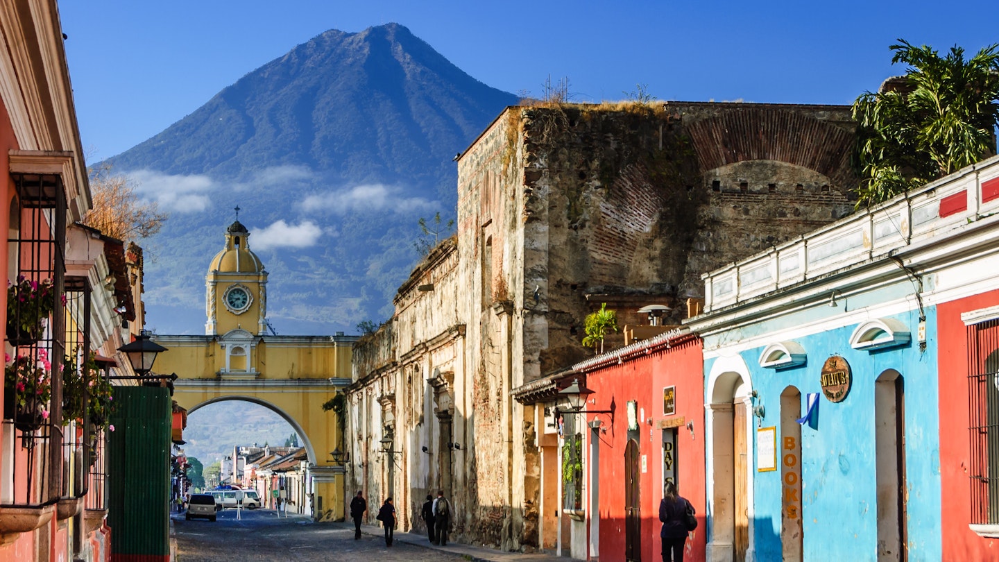 Antigua, Guatemala - March 11, 2012: Agua volcano behind Santa Catalina Arch (allowed nuns to pass to other side of convent without going outside) in colonial town & UNESCO World Heritage Site.