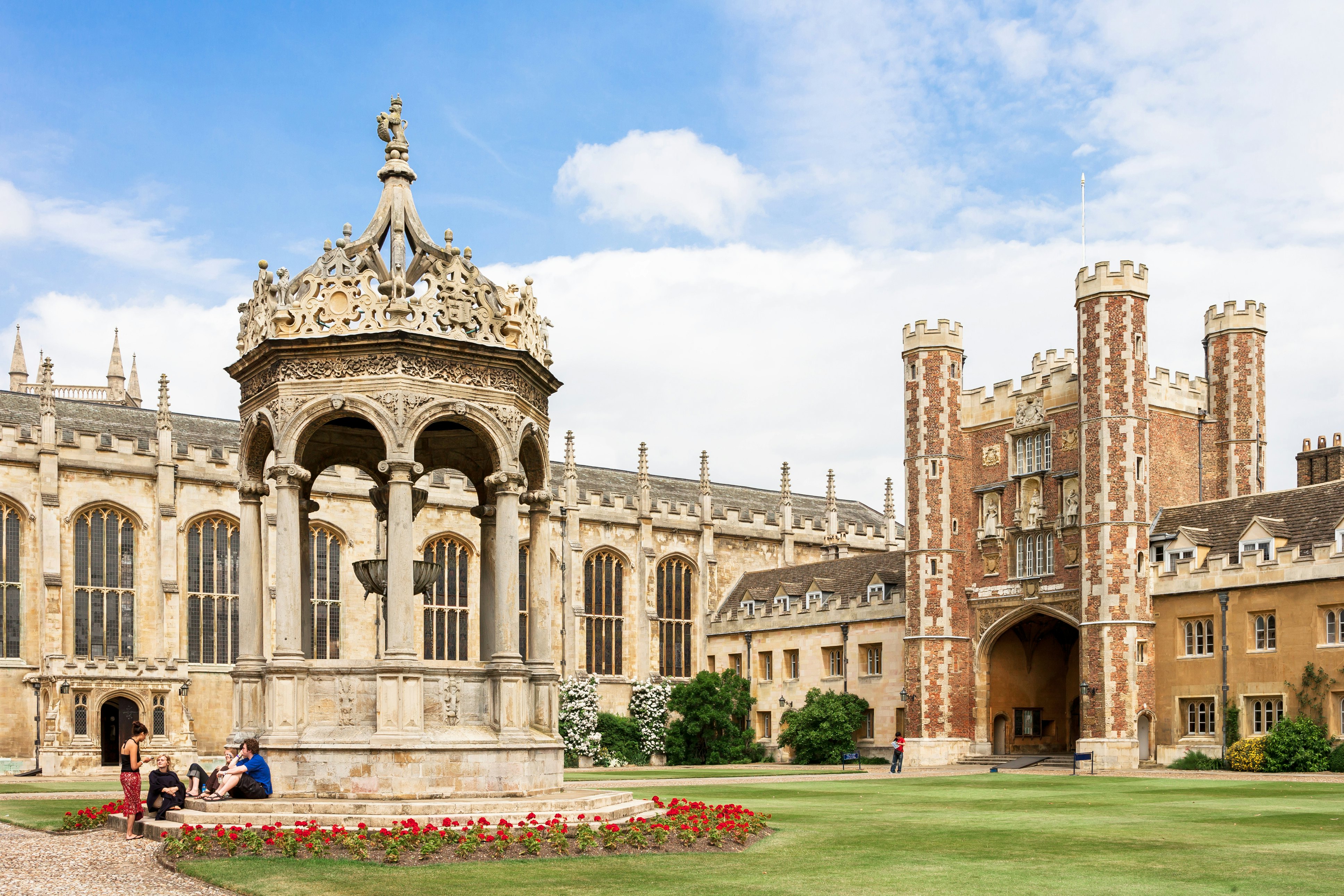 Cambridge, Cambridgeshire, United Kingdom - June 24, 2006: Students in the Great Court of Trinity College in Cambridge University with its historical fountain in the center of the courtyard.