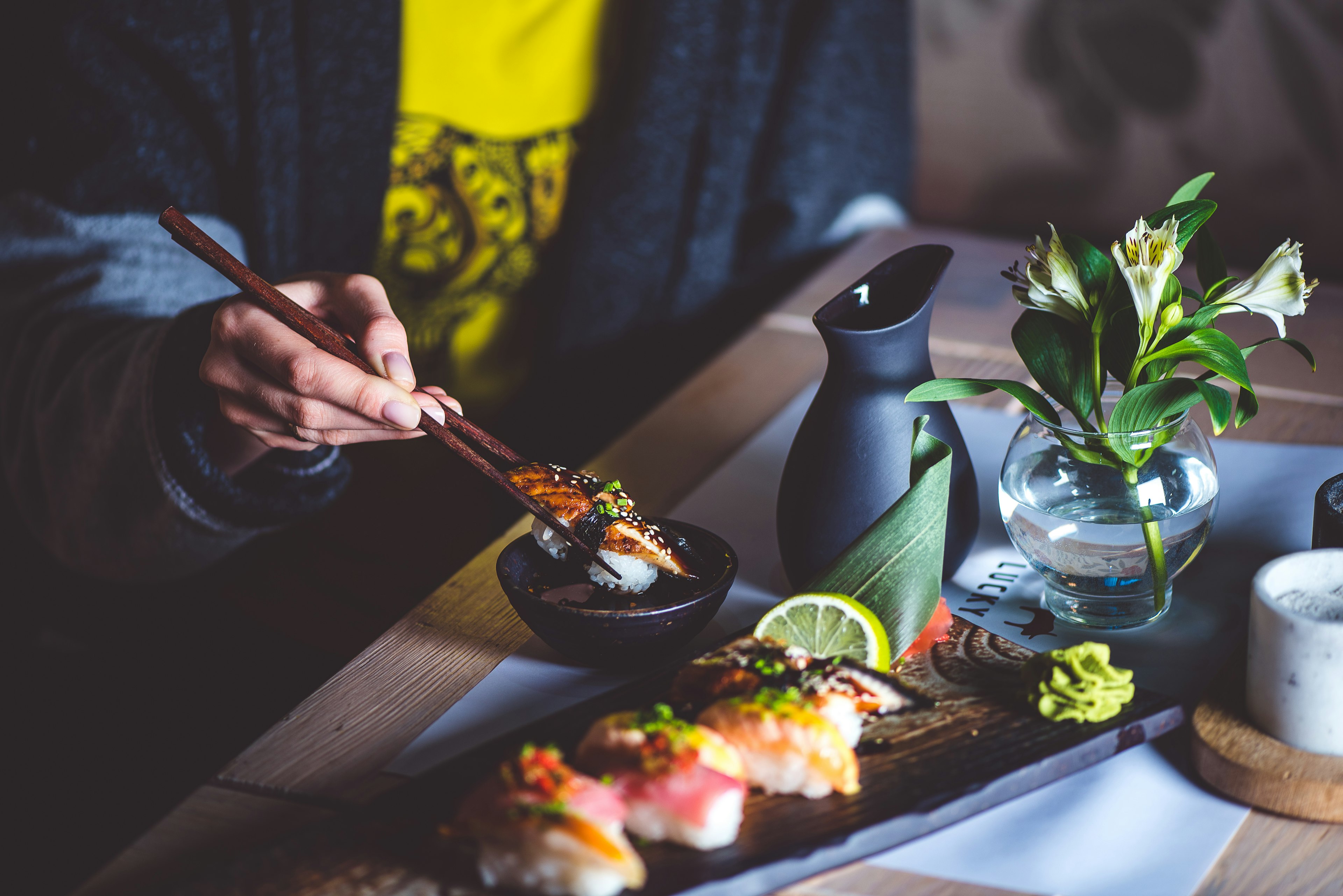 Man eating sushi set with chopsticks at a restaurant.