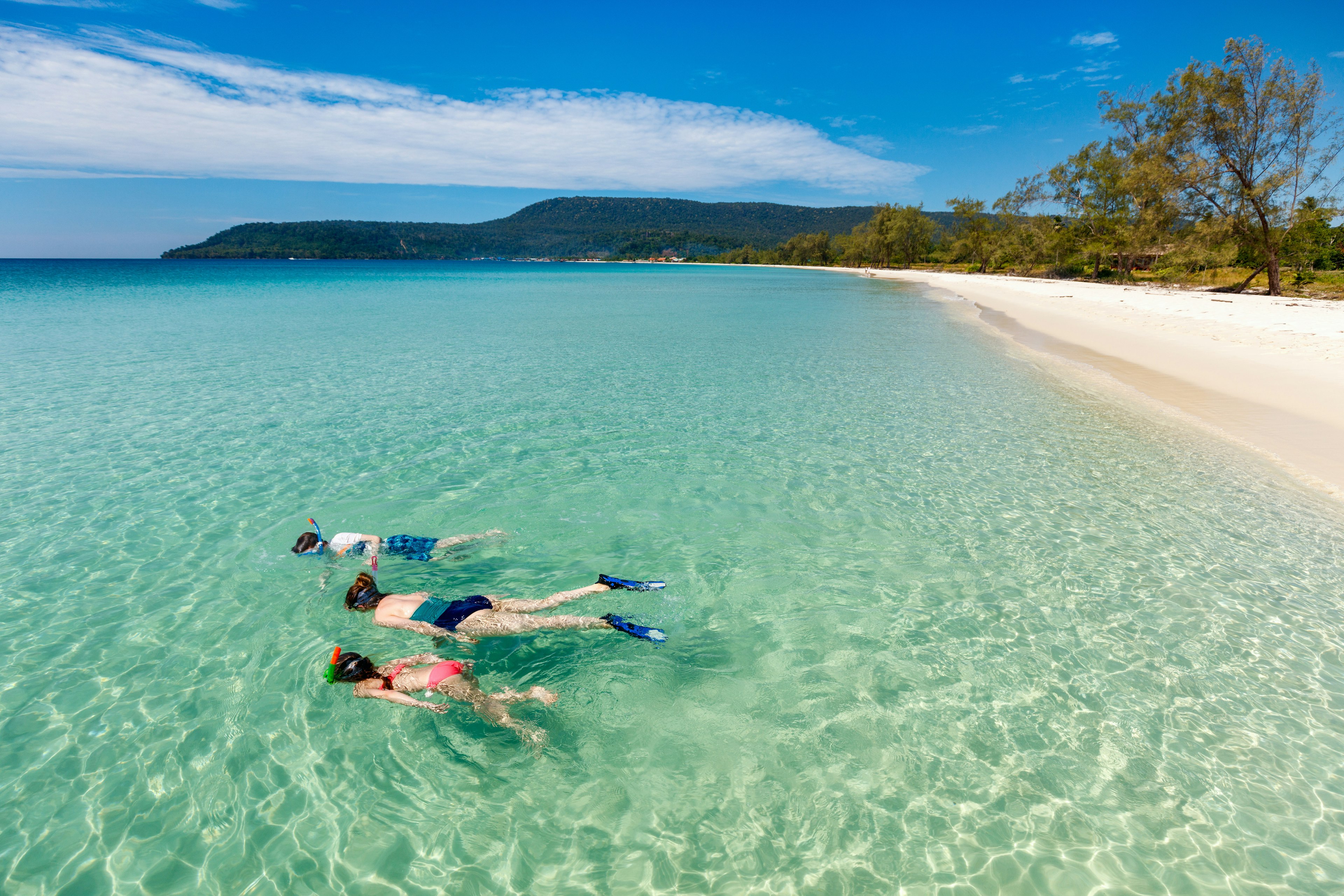 A mother and kids snorkeling in clear tropical water on an empty beach on Koh wrong, Cambodia