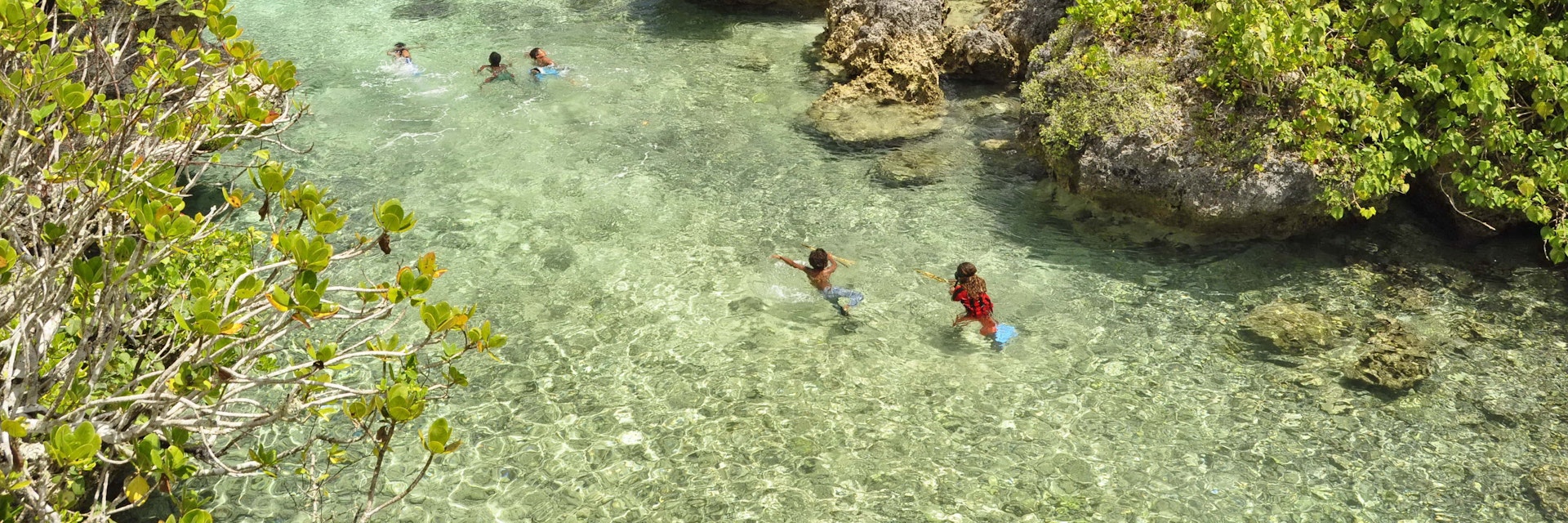 People swimming in a lagoon on Mare Island in New Caledonia.