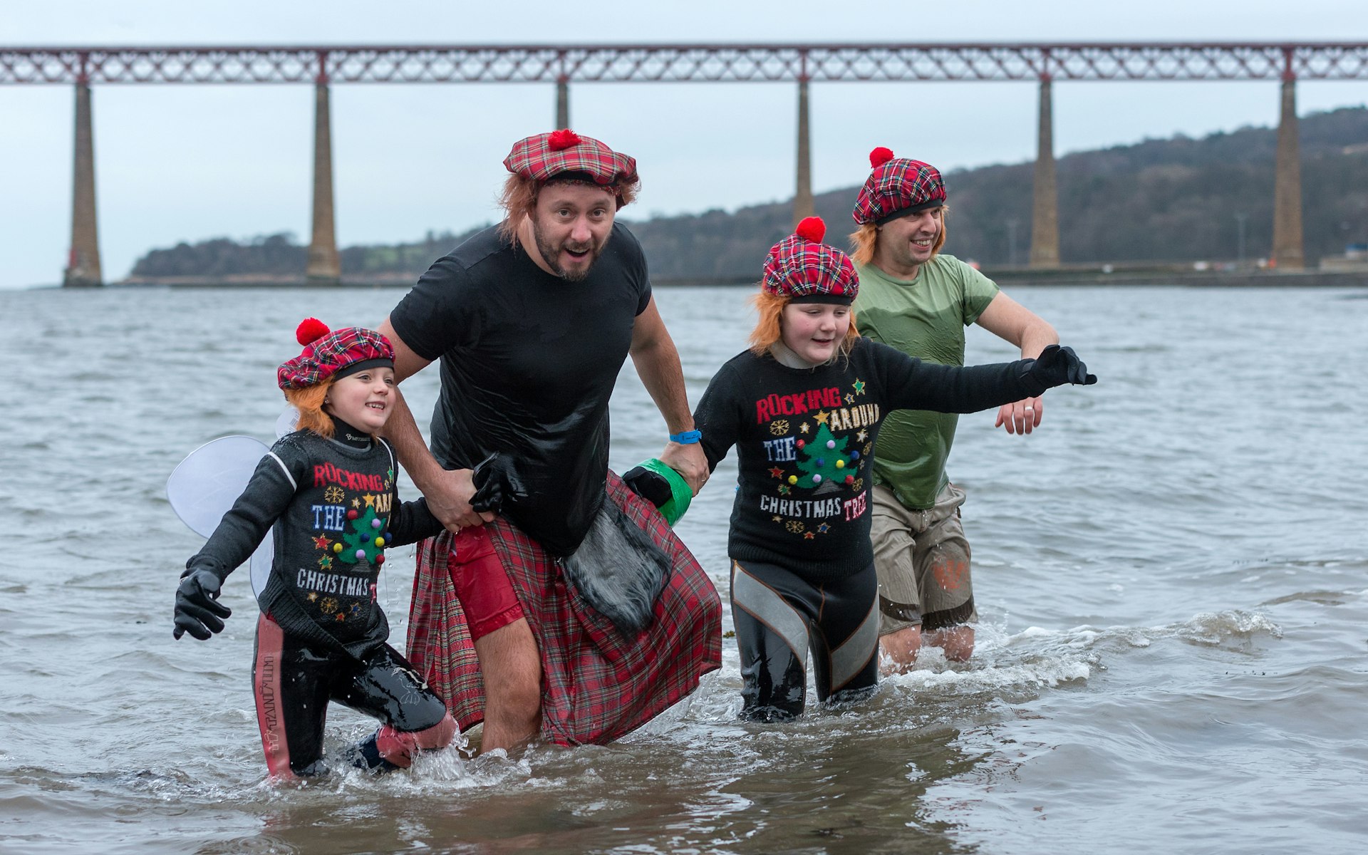 Two men and two children in tartan tams wade into the water for the Annual Loony Dook on New Year’s Day (after Hogmanay) in South Queensferry, Edinburgh