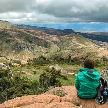 Toro Toro, Potosi / Bolivia - November 4 2018: Girl with a Green Raincoat Sitting in the Edge of a Rock Punt Looking at the Magnificent  Landscape ; Shutterstock ID 1742732099; your: Brian Healy; gl: 65050; netsuite: Lonely Planet Online Editorial; full: Best hikes in Bolivia