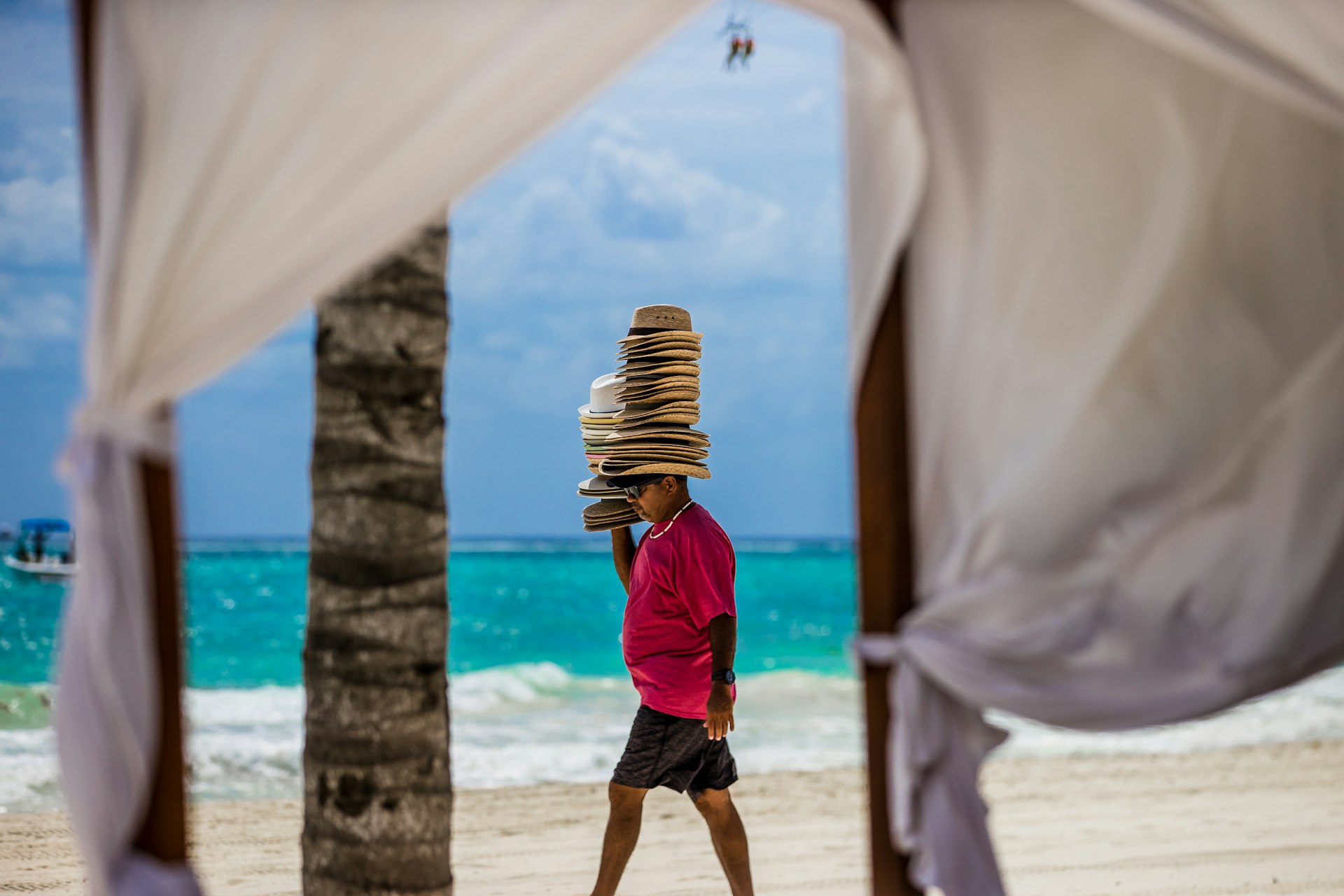 Vendor in Mexico on the beach selling hats while wearing a stack of hats on his head