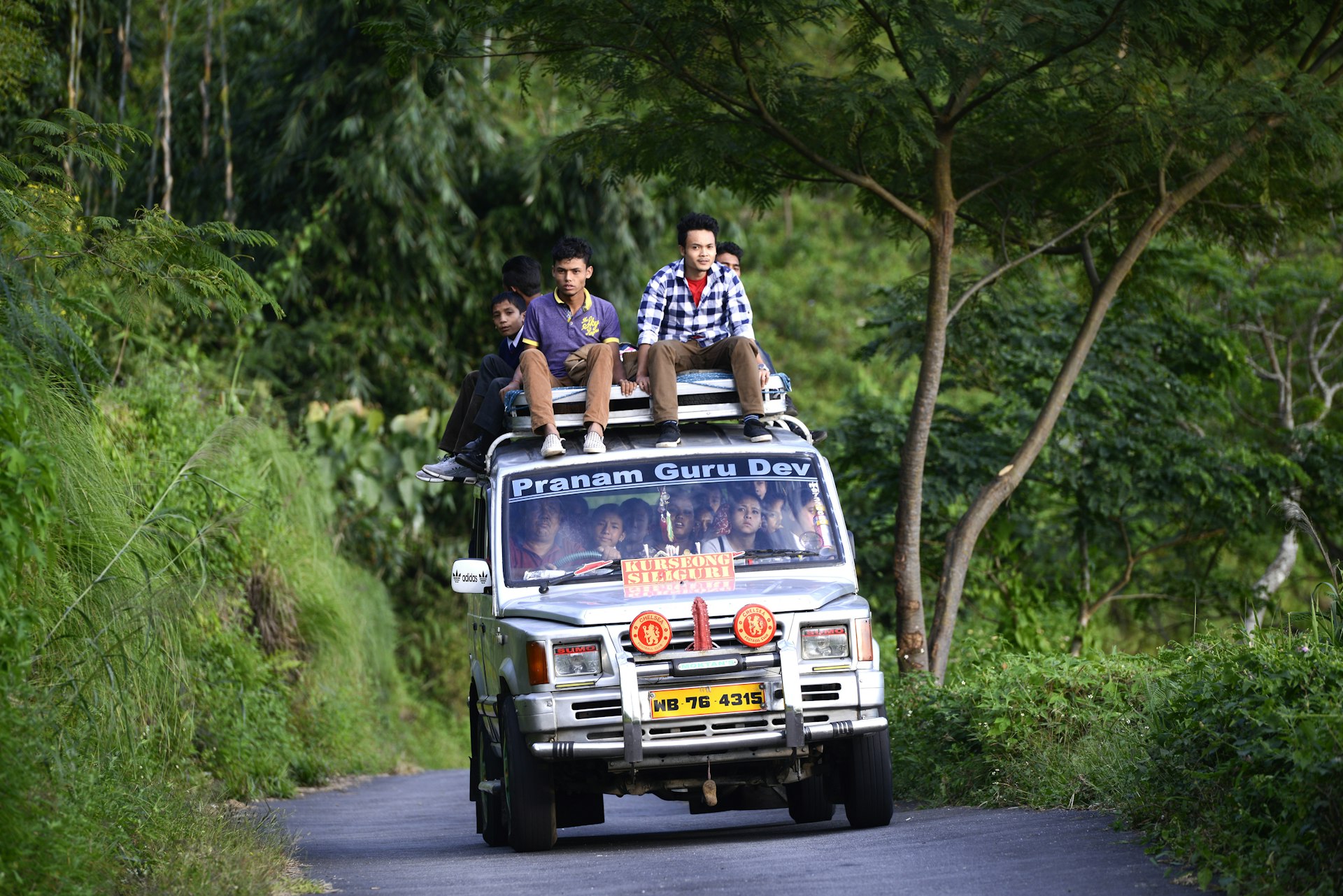 A shared taxi full of passengers on a small mountain road in Darjeeling district, India