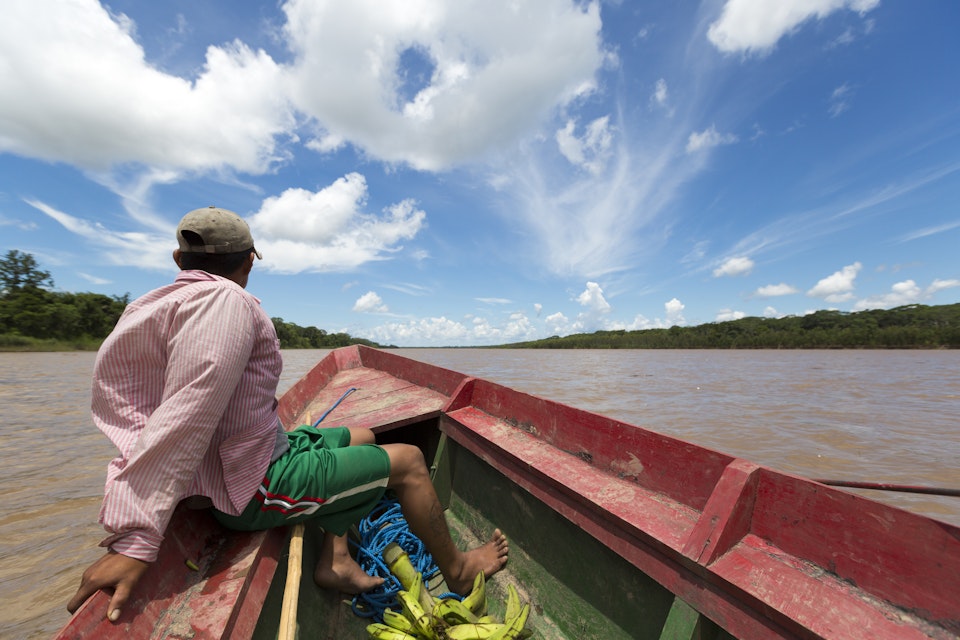 A man in a wooden boat on the Beni River in Madidi National Park, Bolivia
