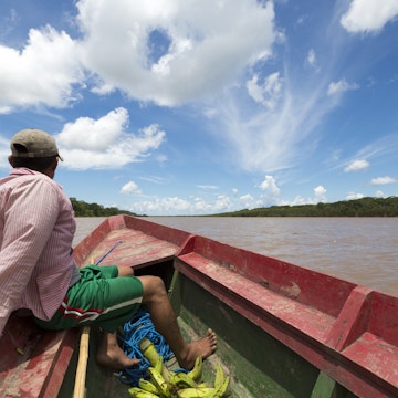 A man in a wooden boat on the Beni River in Madidi National Park, Bolivia