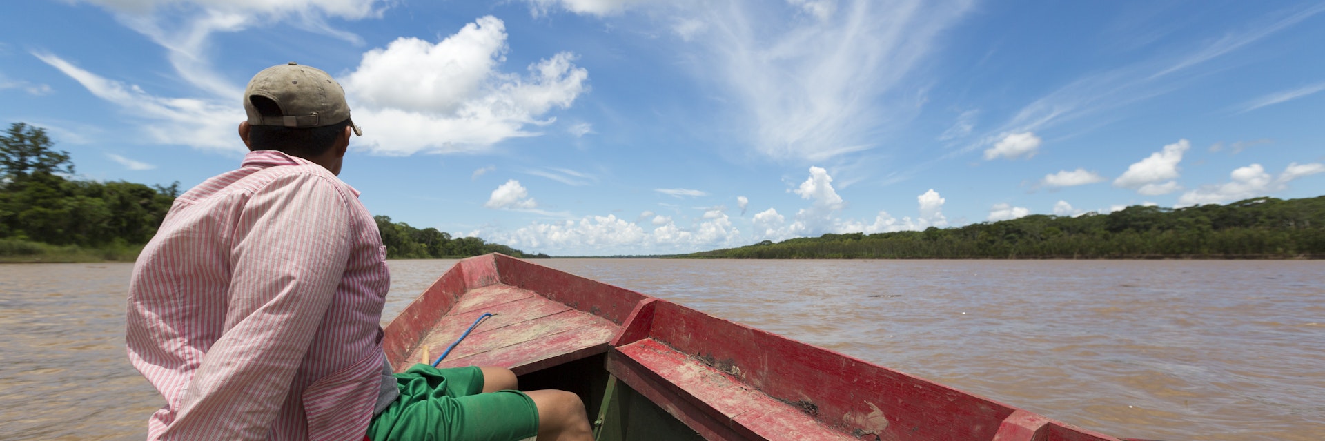 A man in a wooden boat on the Beni River in Madidi National Park, Bolivia