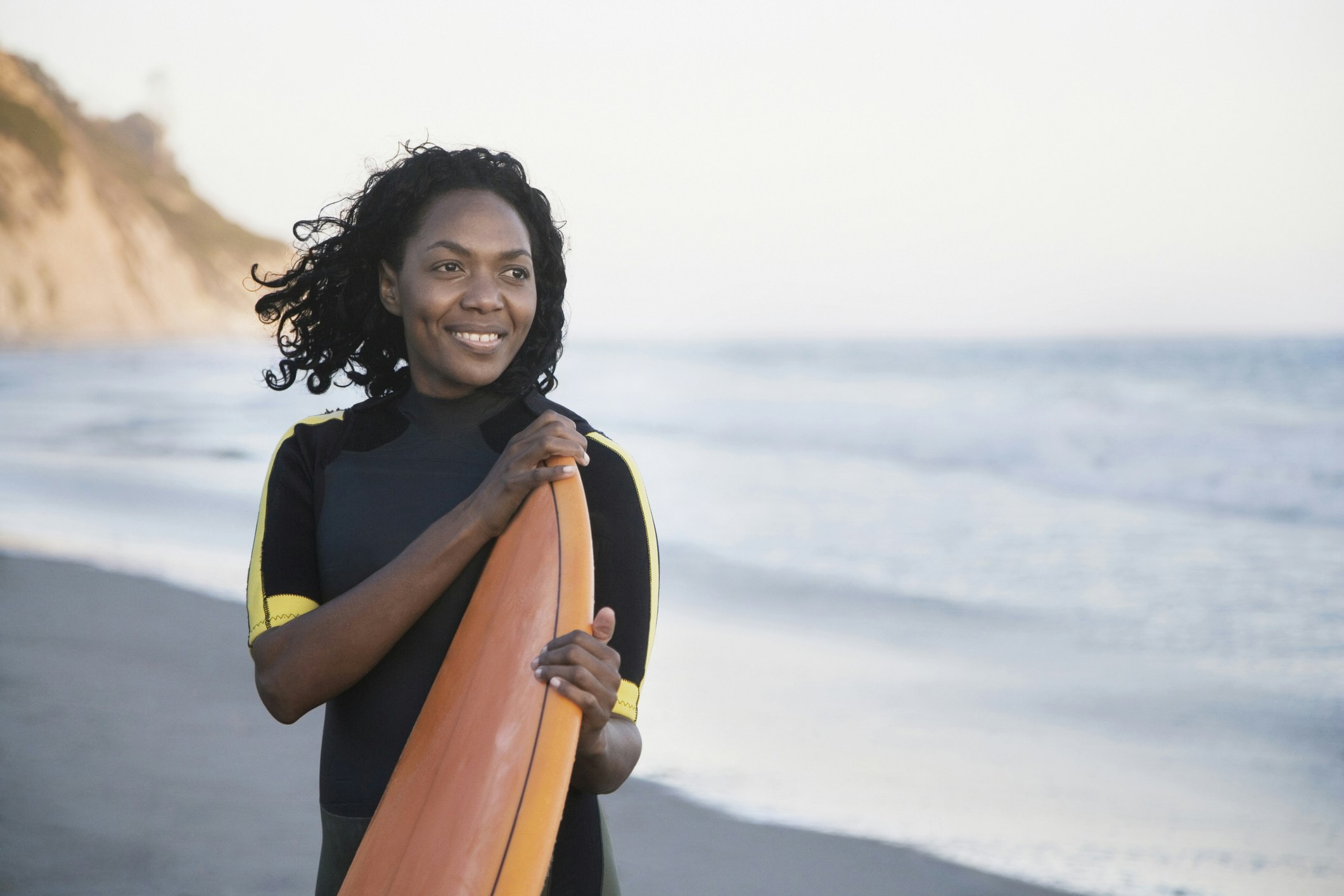 African American woman holding surfboard. 