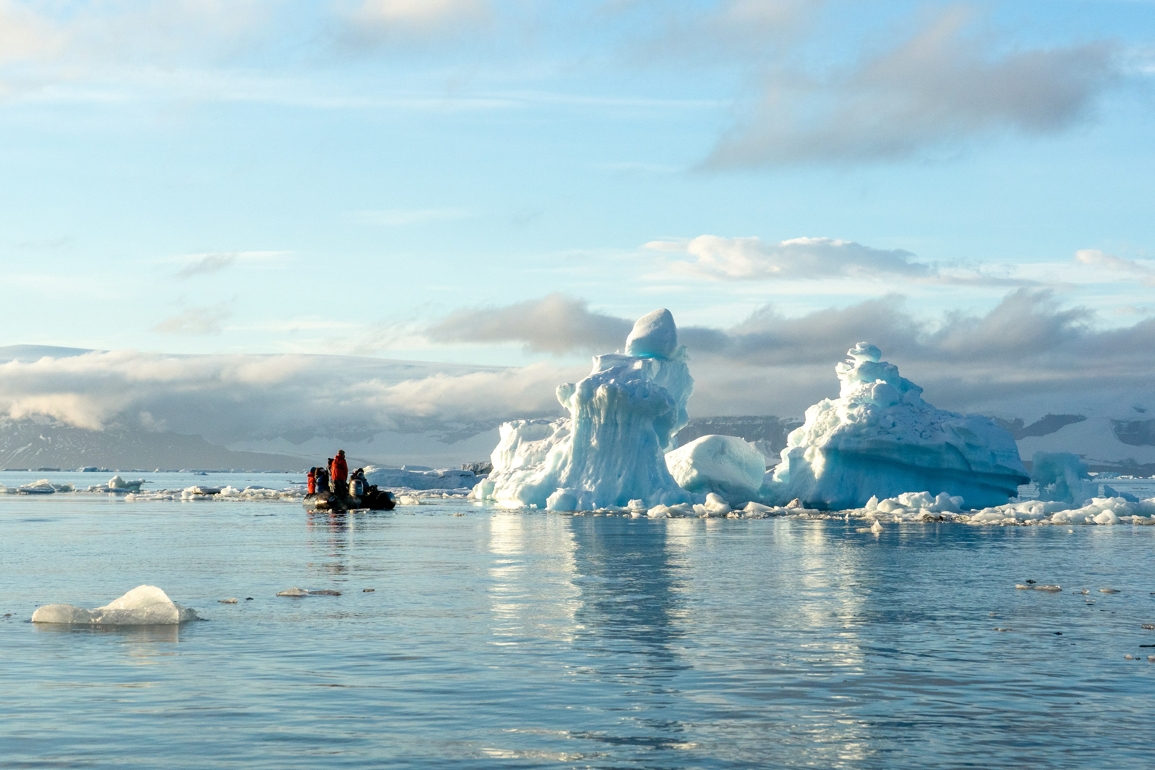 Boat of people passing an iceberg in Weddell Sea.