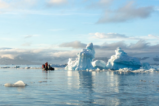 Boat of people passing an iceberg in Weddell Sea.