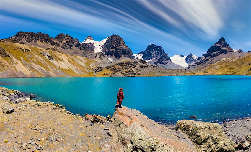 A traveler in a poncho gazes upon the sight of Condoriri Peak in Cordillera Real, Bolivia
