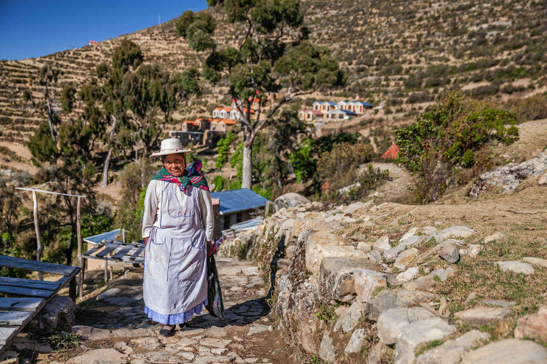 An Aymara woman walking along a stony path on Isla del Sol, Lake Titicaca, Bolivia