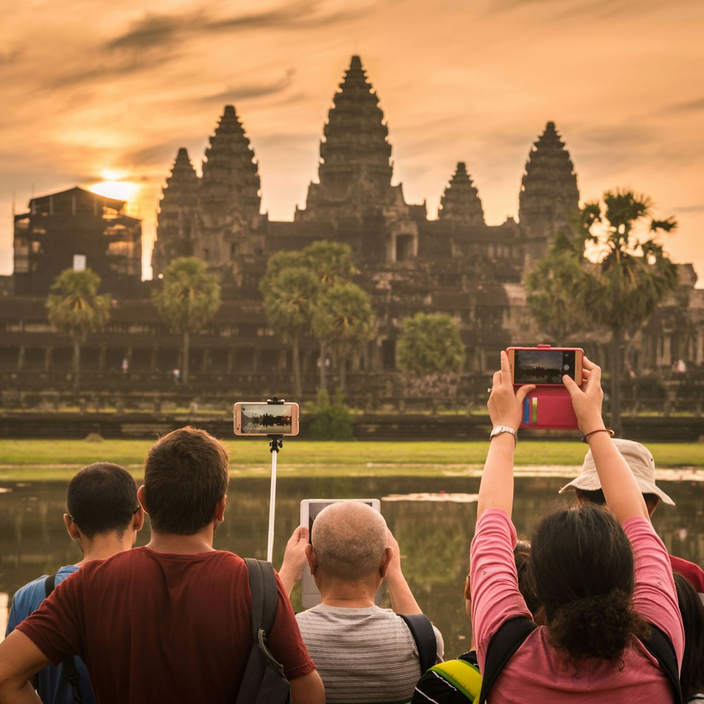 A group of people facing Angkor Wat and taking pictures as the sun comes up