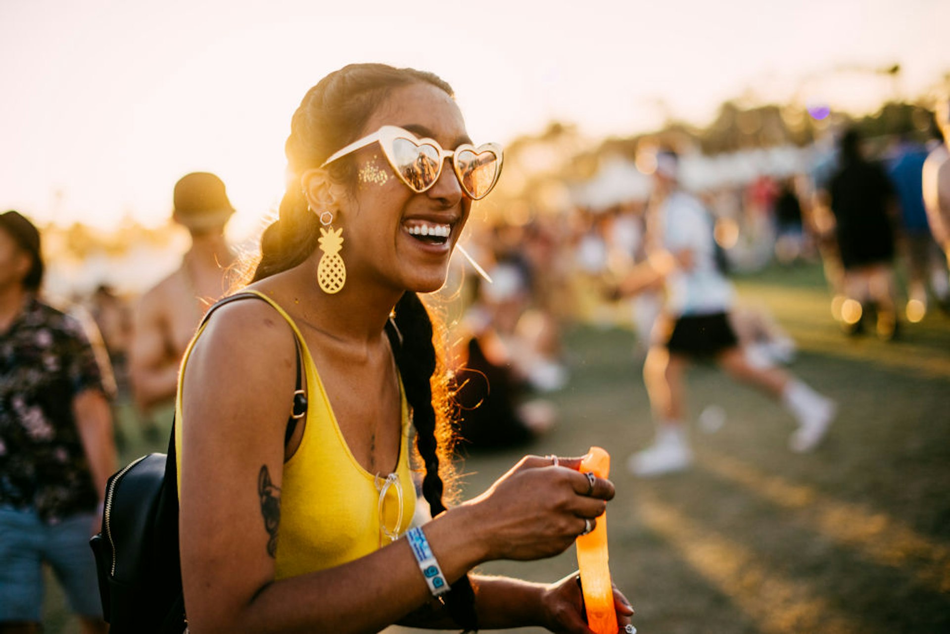 A woman blow bubbles in a yellow shirt at the Coachella music festival. 