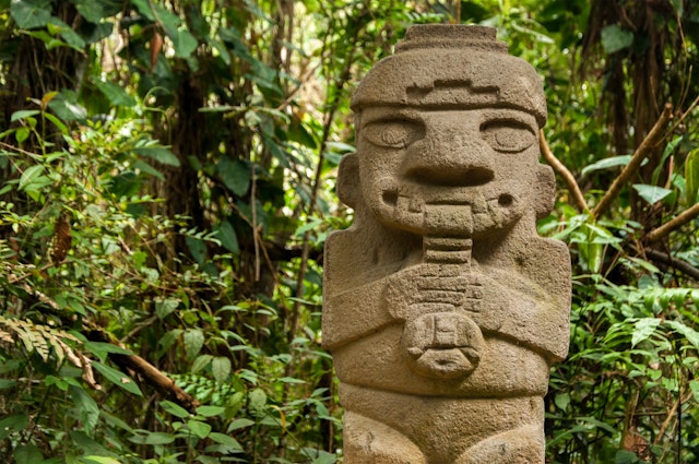 A pre-Columbian stone figure of a flute-playing person at Parque Arqueológico San Agustín, Colombia