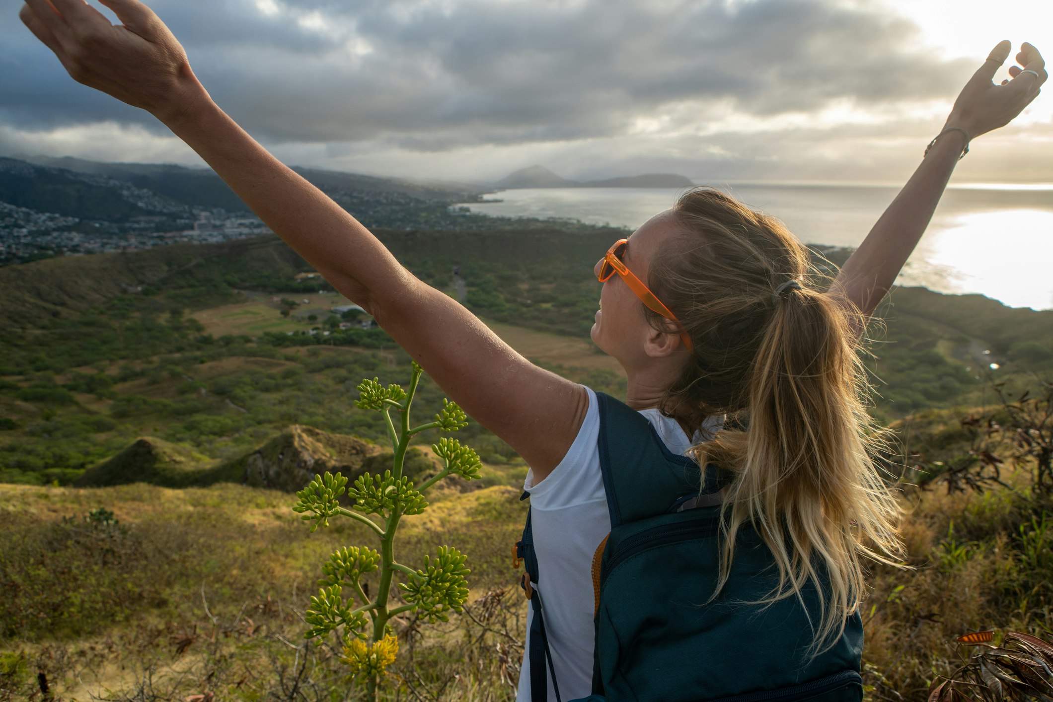Young woman on mountain top arms outstretched, Honolulu, Hawaii, USA