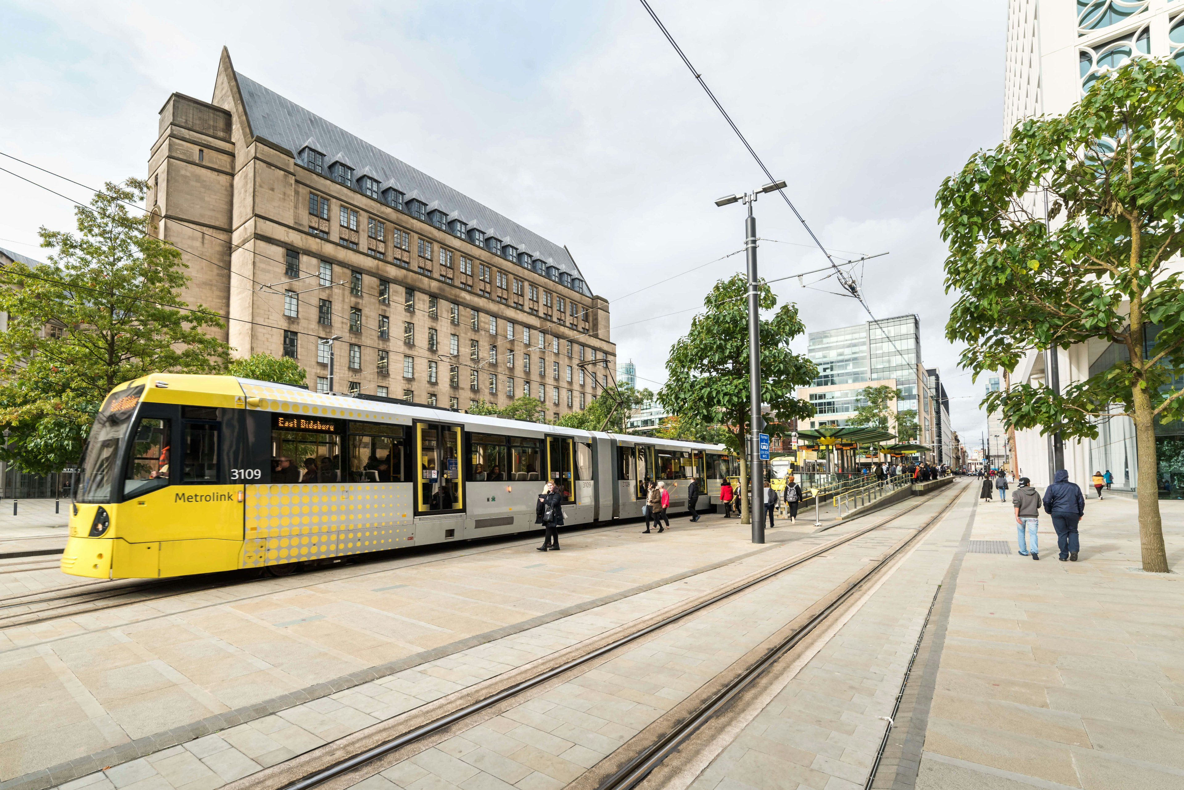 People walking to and alongside the Metrolink tram at St Peter's Square, Manchester