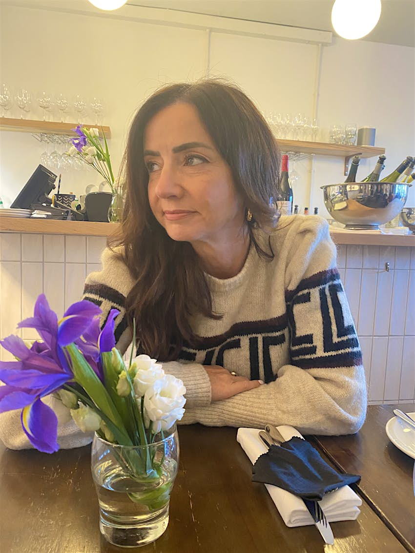 Fionnuala McCarthy sits at a table with flowers on it and wine in the background. 