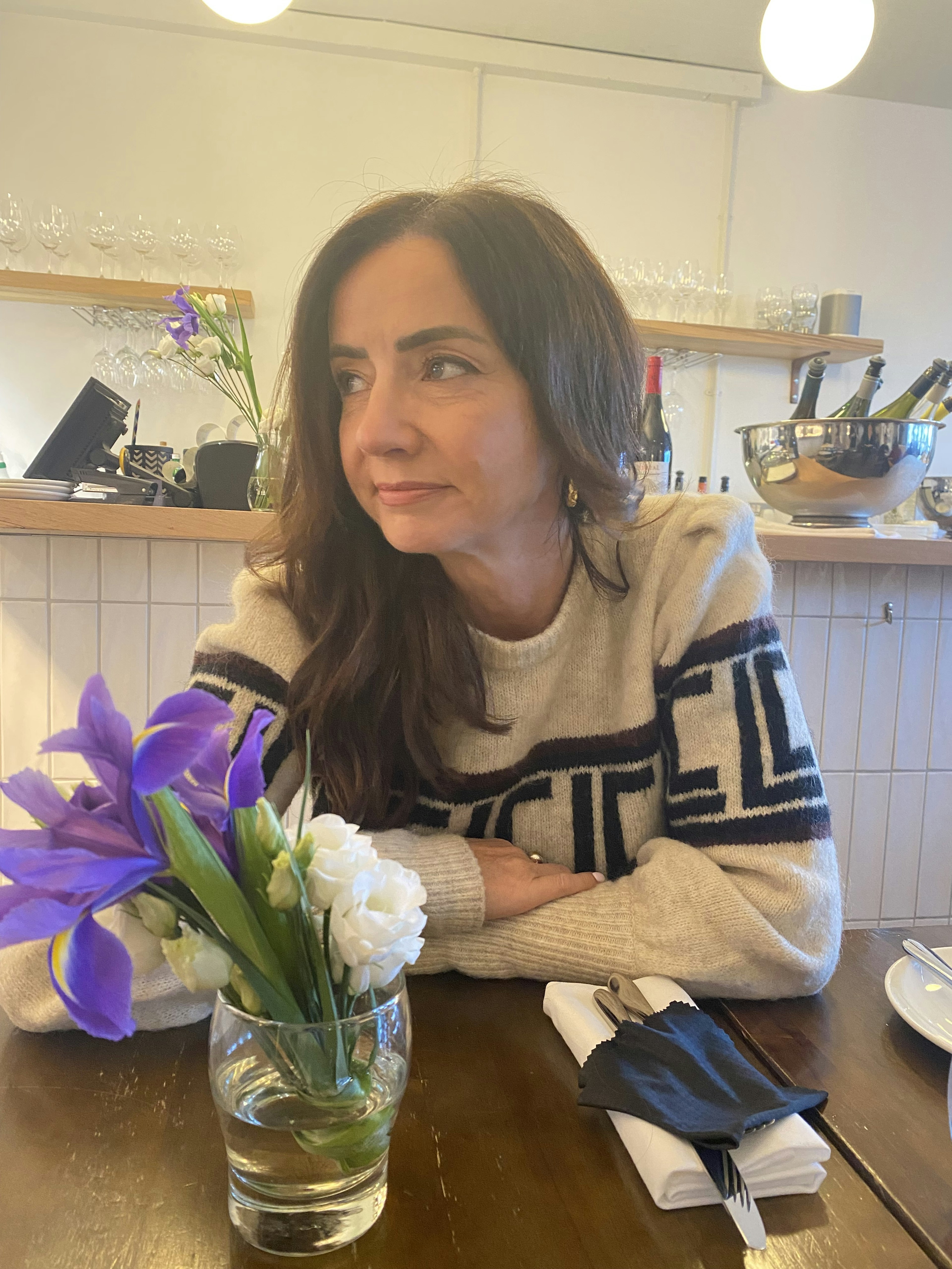 Fionnuala McCarthy sits at a table with flowers on it and wine in the background.