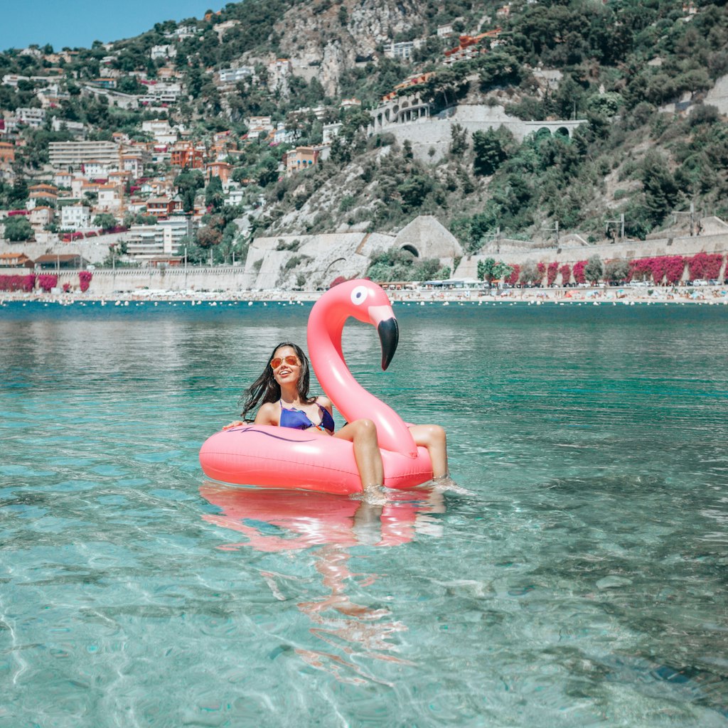 Happy girl on flamingo floating on clear water in Nice,France - stock photo
