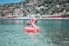 Happy girl on flamingo floating on clear water in Nice,France - stock photo
