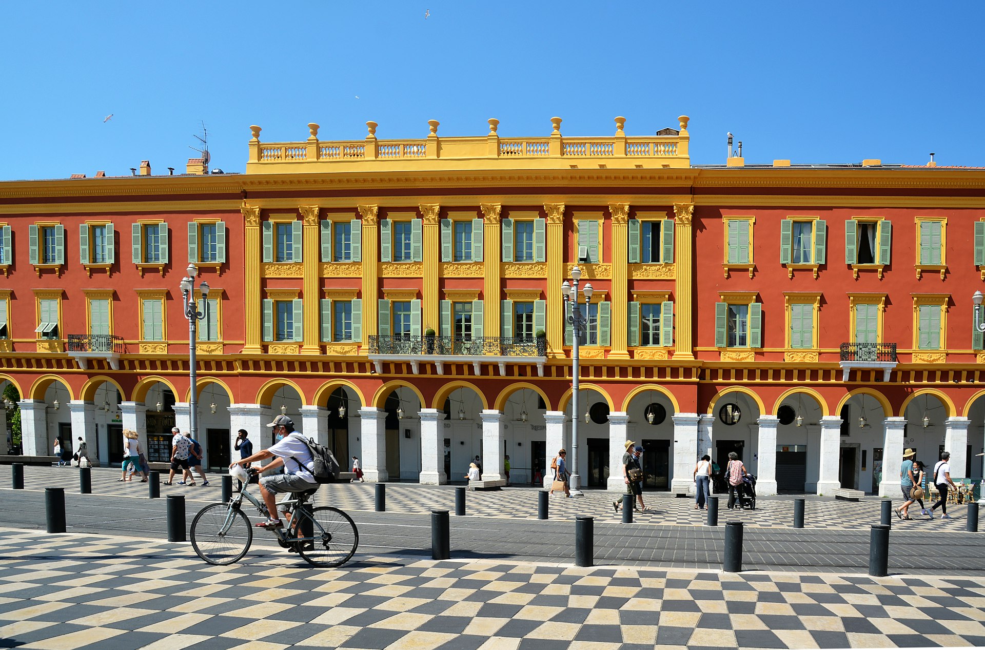 A man riding a bicycle past Place Masséna in Nice, France