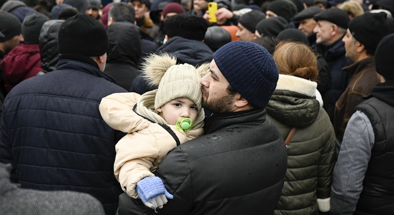 TOPSHOT - A man holds his child as families, who fled Ukraine due to the Russian invasion, wait to enter a refugee camp in the Moldovan capital Chisinau on March 3, 2022. (Photo by Nikolay DOYCHINOV / AFP) (Photo by NIKOLAY DOYCHINOV/AFP via Getty Images)
