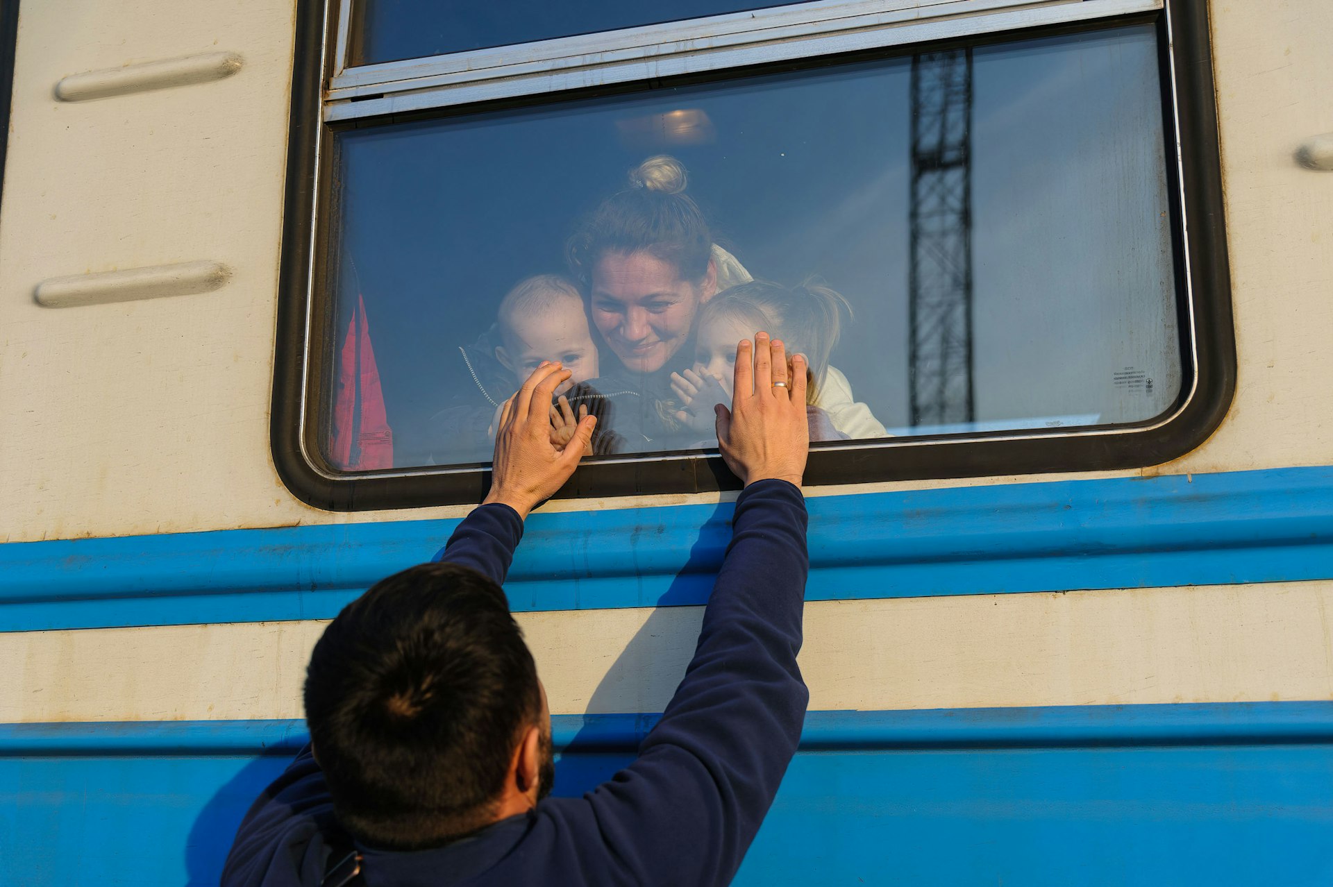 A man gestures to his family outside a train to Poland at