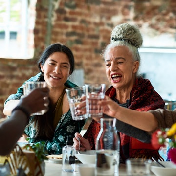 Small group of people holding water glasses at lunch table, celebration, smiling, happiness, bonding