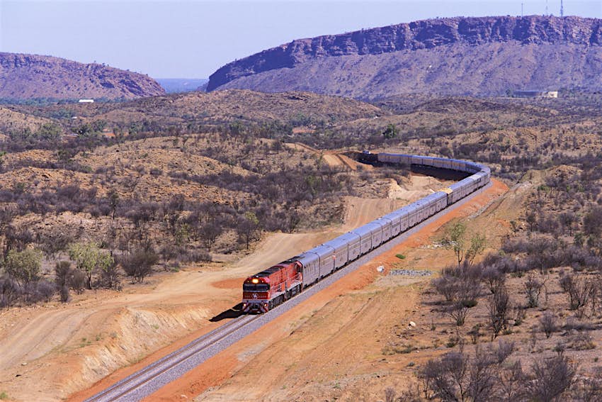 The Ghan train to Darwin, departing Alice Springs with the MacDonnell Ranges in the background