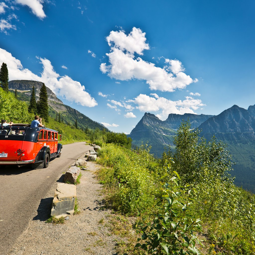 Glacier National Park, Montana, USA - August 2, 2016: Visitors to Glacier National Park touring the park along the breathtaking "Going To The Sun Road" in cars or in park tour buses. The scenic road wind through the national park along steep mountain cliffs and valleys.