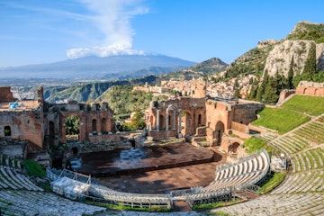 The Greek theatre (Teatro Greco) and Mount Etna, Taormina, Sicily; The Greek theatre with smoking Mount Etna volcano in the background, Taormina, Sicily, Italy