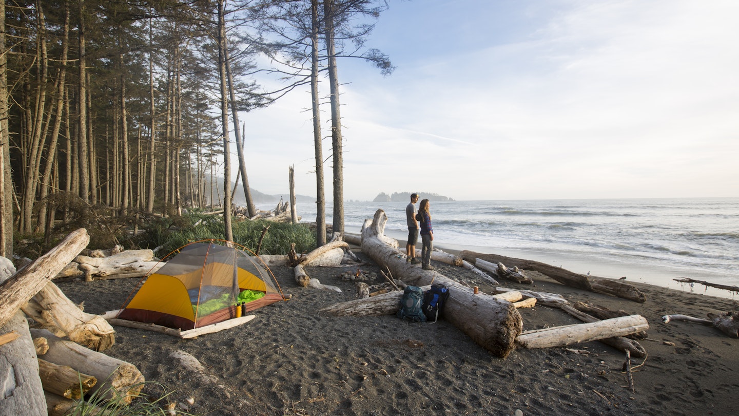 Backpacking along a beach - a couple watching the sunset while backpacking along the coast in the Olympic National Park.