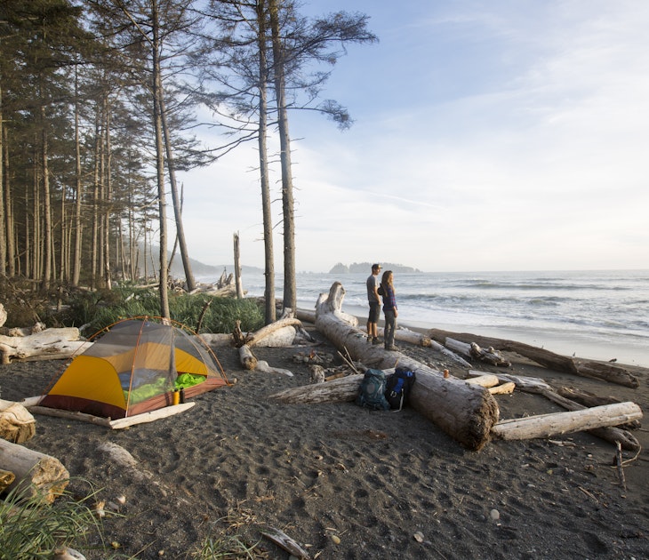 Backpacking along a beach - a couple watching the sunset while backpacking along the coast in the Olympic National Park.