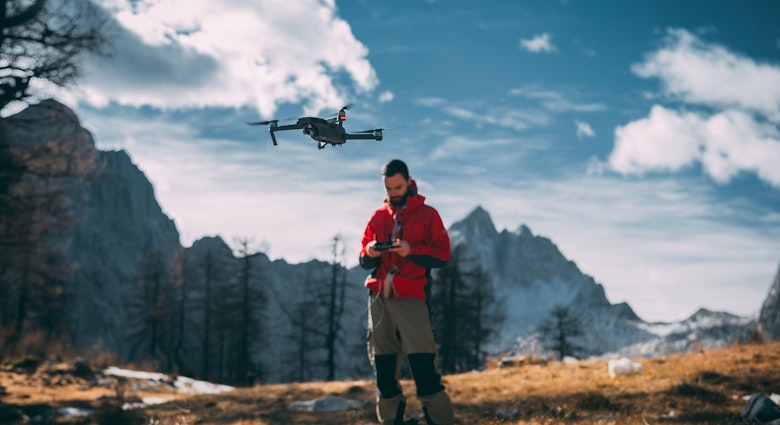 Man Flying Drone Against Mountains