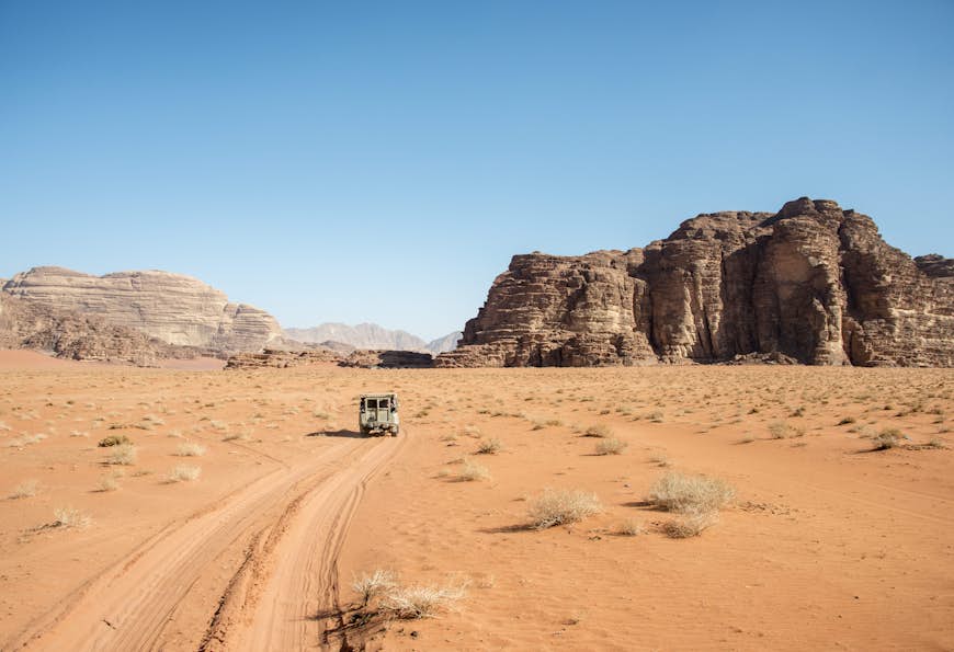 Pick-up truck driving through the desert of Wadi Rum. 