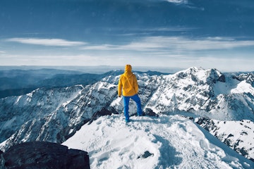 Alpinist standing on the snow-covered peak of Jebel Toubkal mountain.
