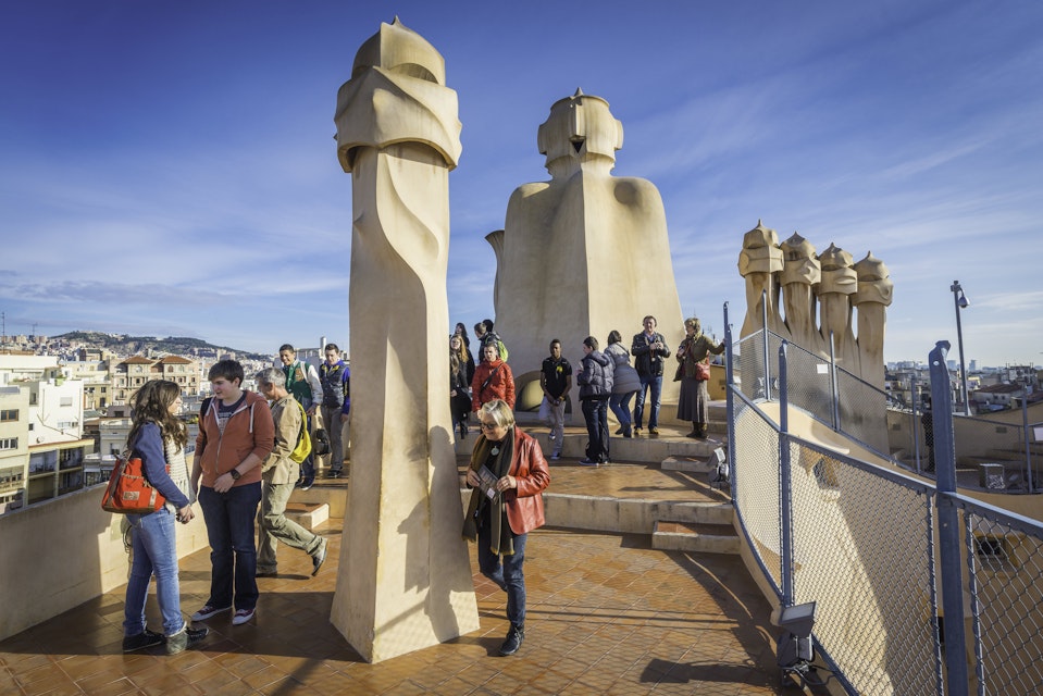 Barcelona, Spain - 14th February 2013: Tourists enjoying their visit to the rooftop of Casa Mila, La Pedrera, to see the iconic Gaudi chimneys that overlook the Sagrada Familia and the heart of downtown Barcelona, Spain.