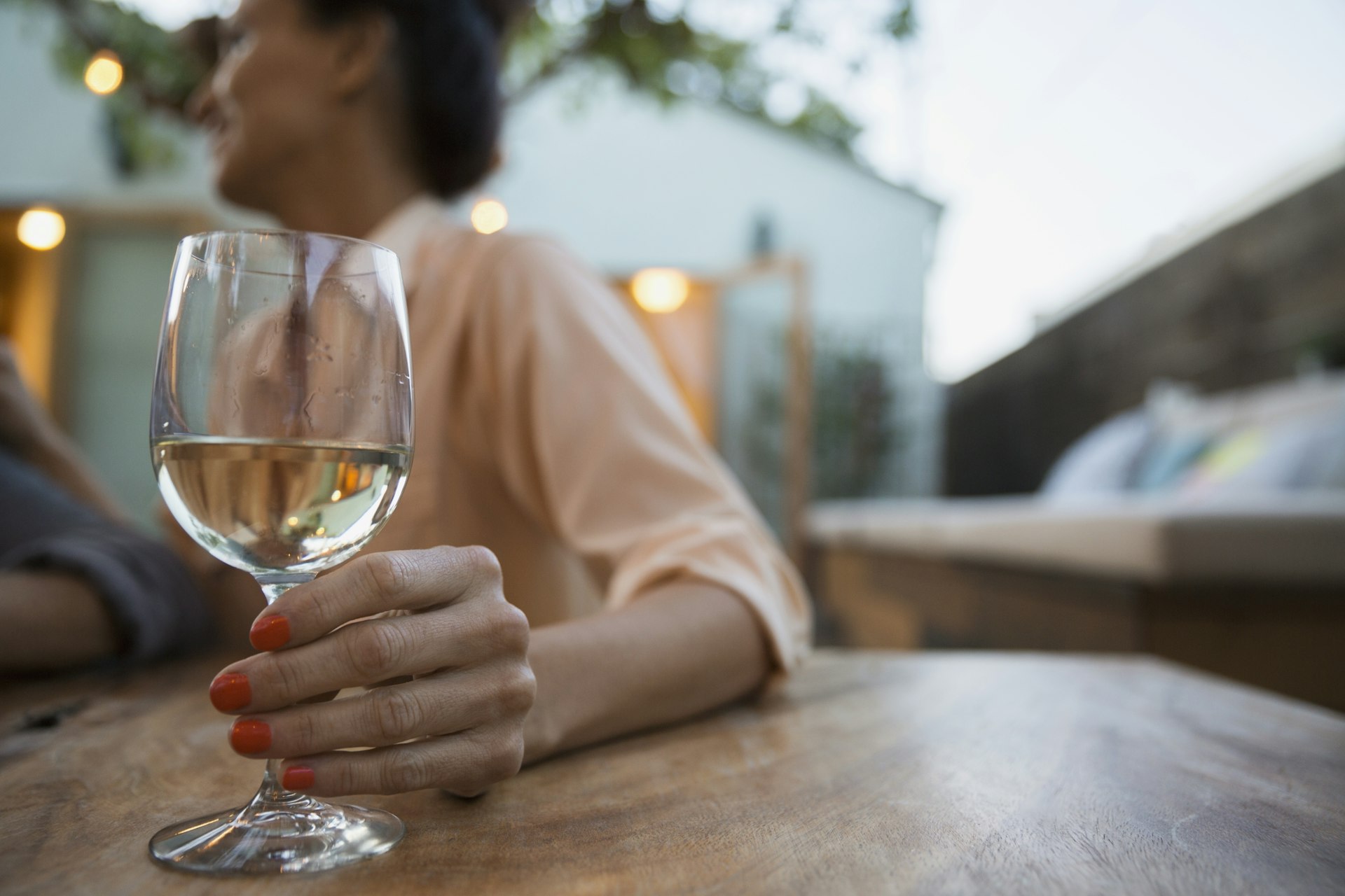 Woman holds a glass filled with white wine on patio